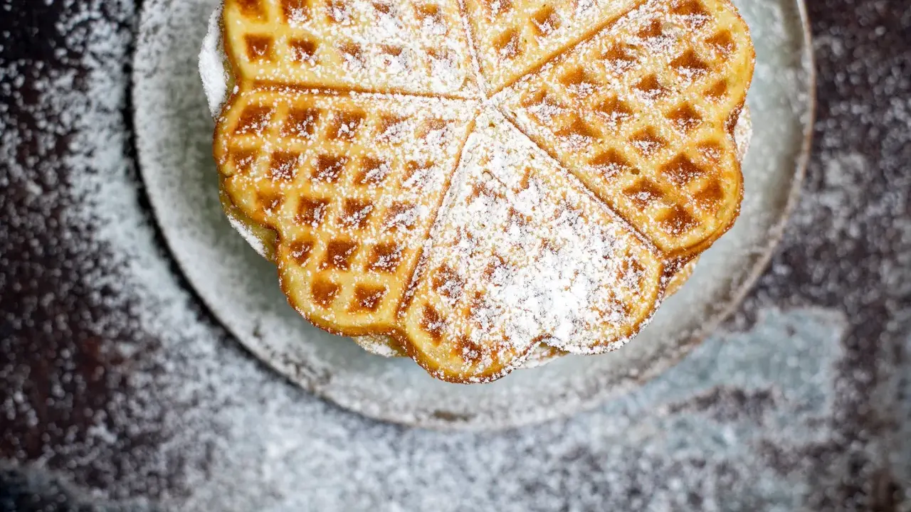 Herzförmige Waffeln, bestäubt mit Puderzucker, sehen aus wie aus einem perfekten Waffeln Rezept.
