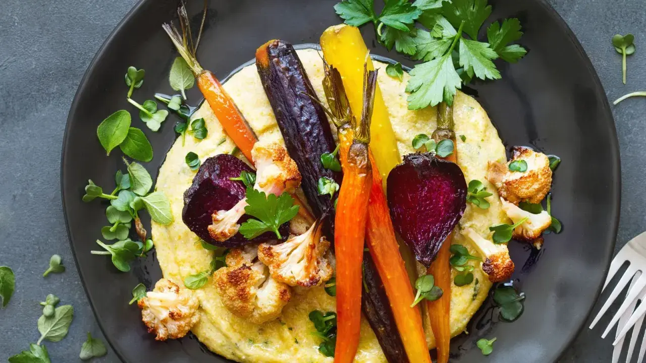 Bunte Wurzelgemüse und Blumenkohl auf cremiger Polenta – eine köstliche Idee, was passt zu Polenta vegetarisch.