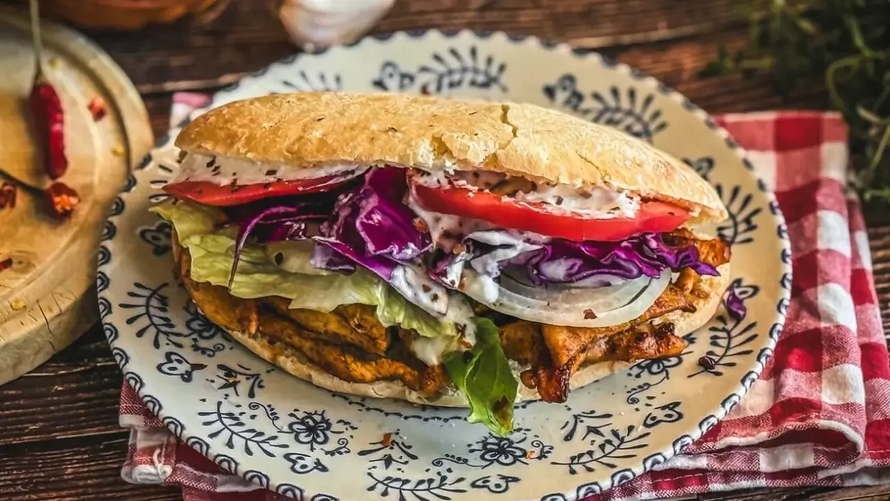 Saftiger Döner Kebab mit Fleisch, Salat, Tomaten, Zwiebeln und Rotkohl auf einem Teller. Ein leckeres Kebab Rezept zum Nachmachen.