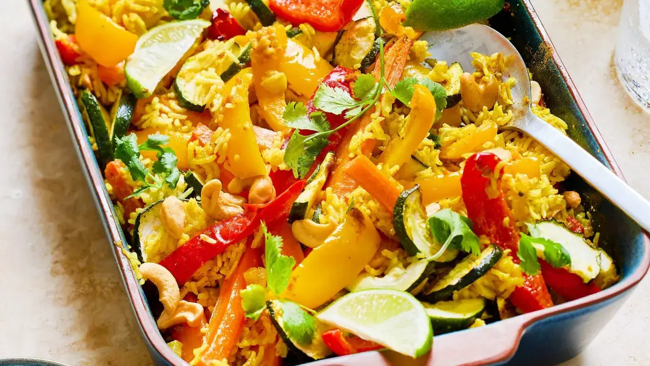 Buntes Gericht mit Reis, Paprika, Zucchini, Karotten und Cashewkernen, garniert mit Koriander und Limettenspalten. Ein köstliches Gericht mit Reis für jeden Anlass.