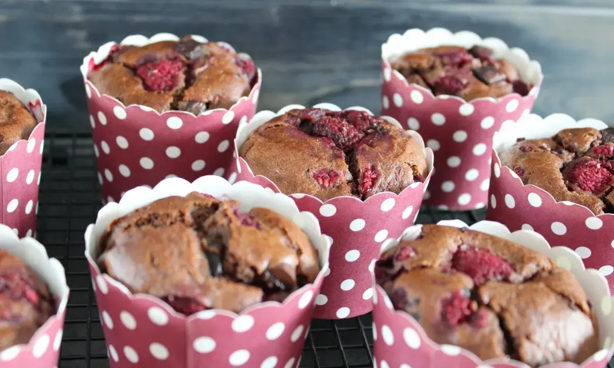 Saftige schokomuffins mit Himbeeren, gebacken in rot-weißen Pünktchen-Förmchen, warten auf ihren Genuss.