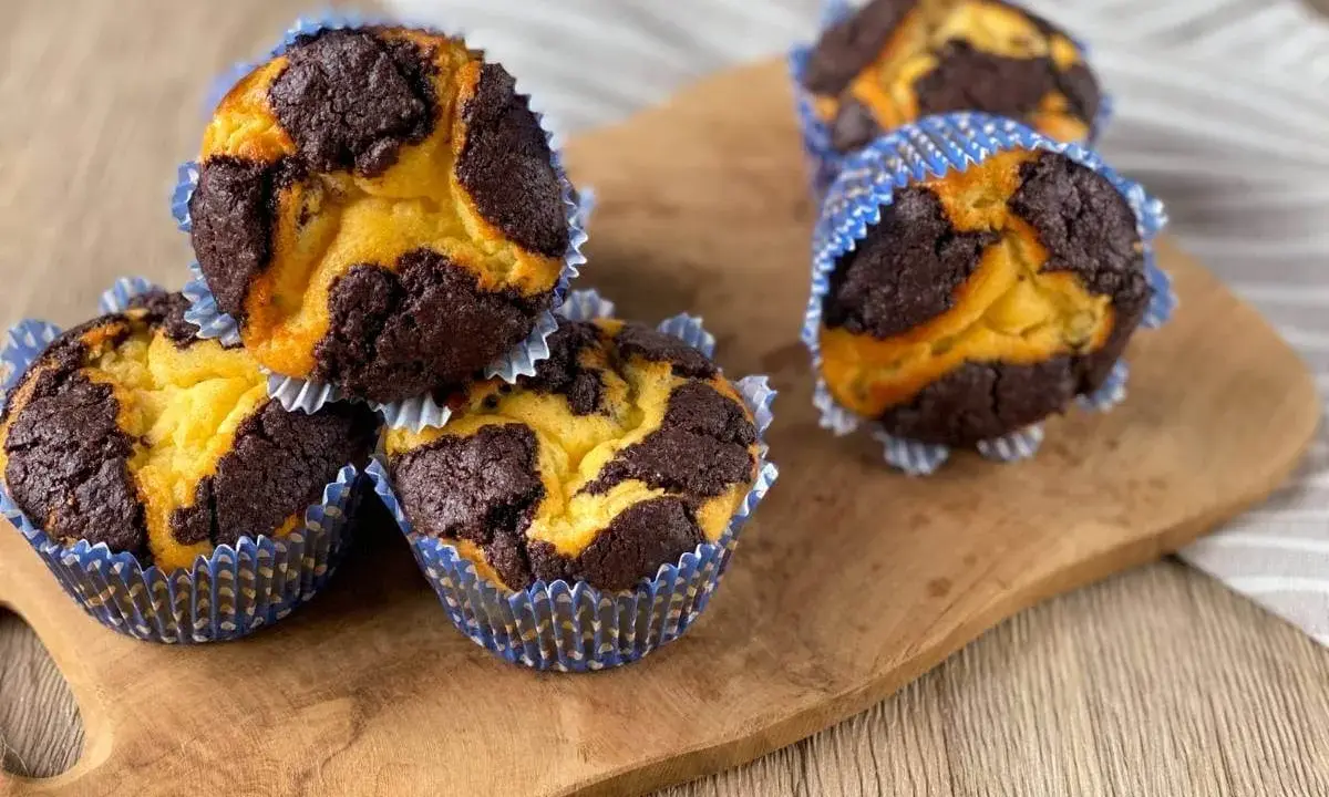 Zupfkuchen Muffins mit Schoko-Marmorierung in blauen Papierförmchen auf einem Holzbrett.