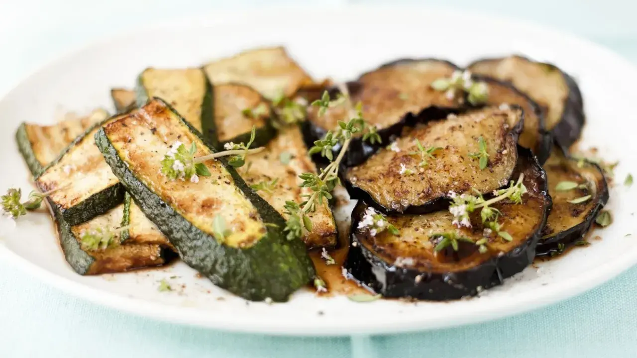 Gebratene Zucchini und Auberginen, italienisch gewürzt mit Kräutern, auf einem Teller.