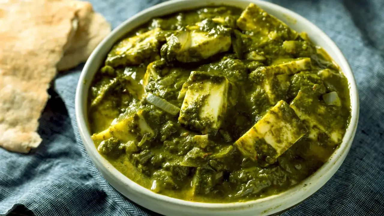 Schüssel mit cremigem Palak Paneer, einem indischen Gericht aus Spinat und Käse, daneben Fladenbrot.