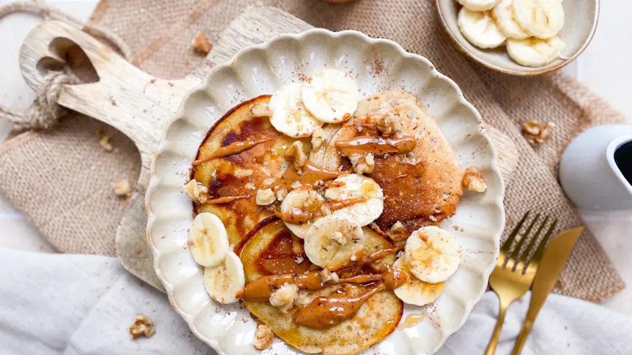 Bananen Pancakes ohne Ei, garniert mit Bananenscheiben, Nüssen und einer cremigen Sauce. Ein köstlicher Brunch-Traum!