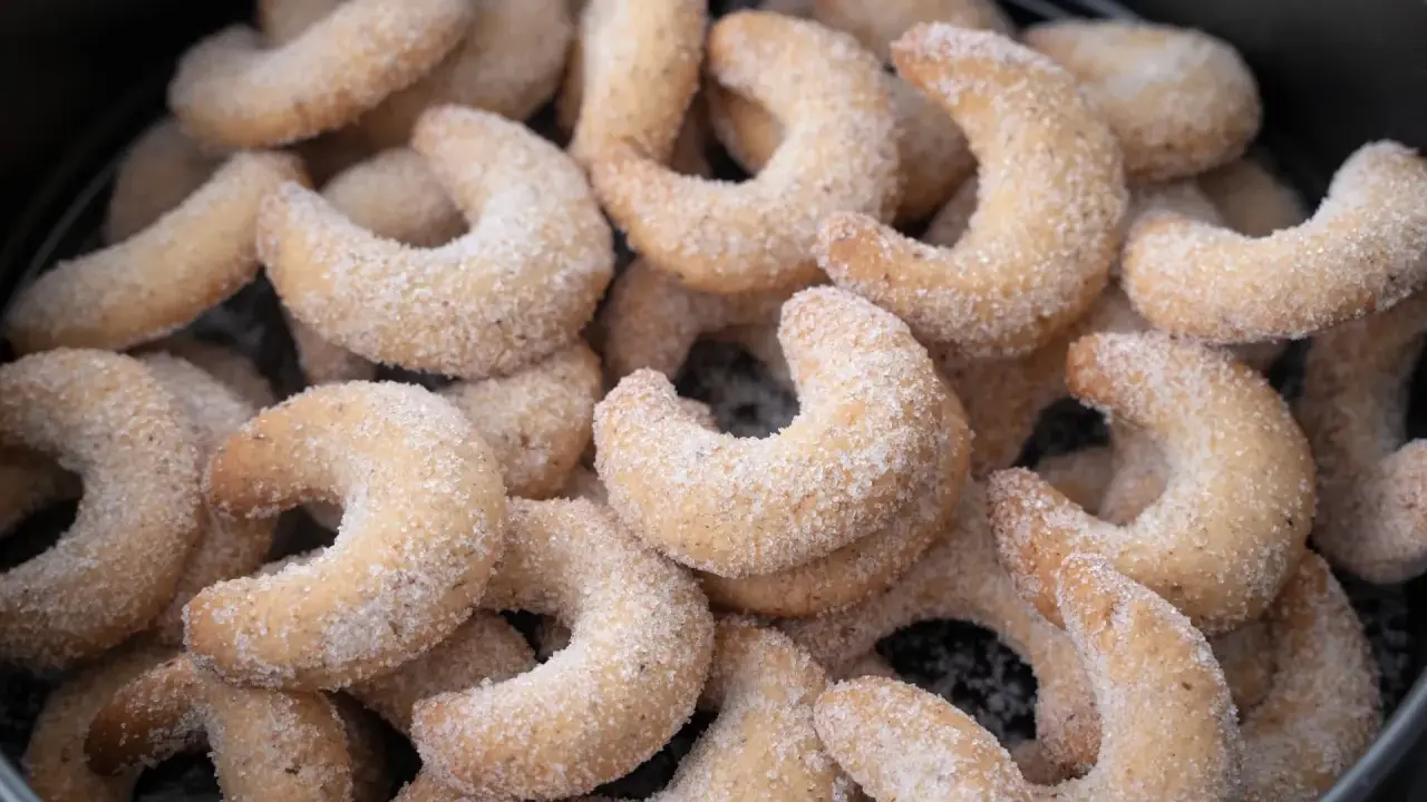 Ein Haufen frisch gebackener Vanillekipferl, bedeckt mit feinem Zucker, wartet darauf, genossen zu werden.