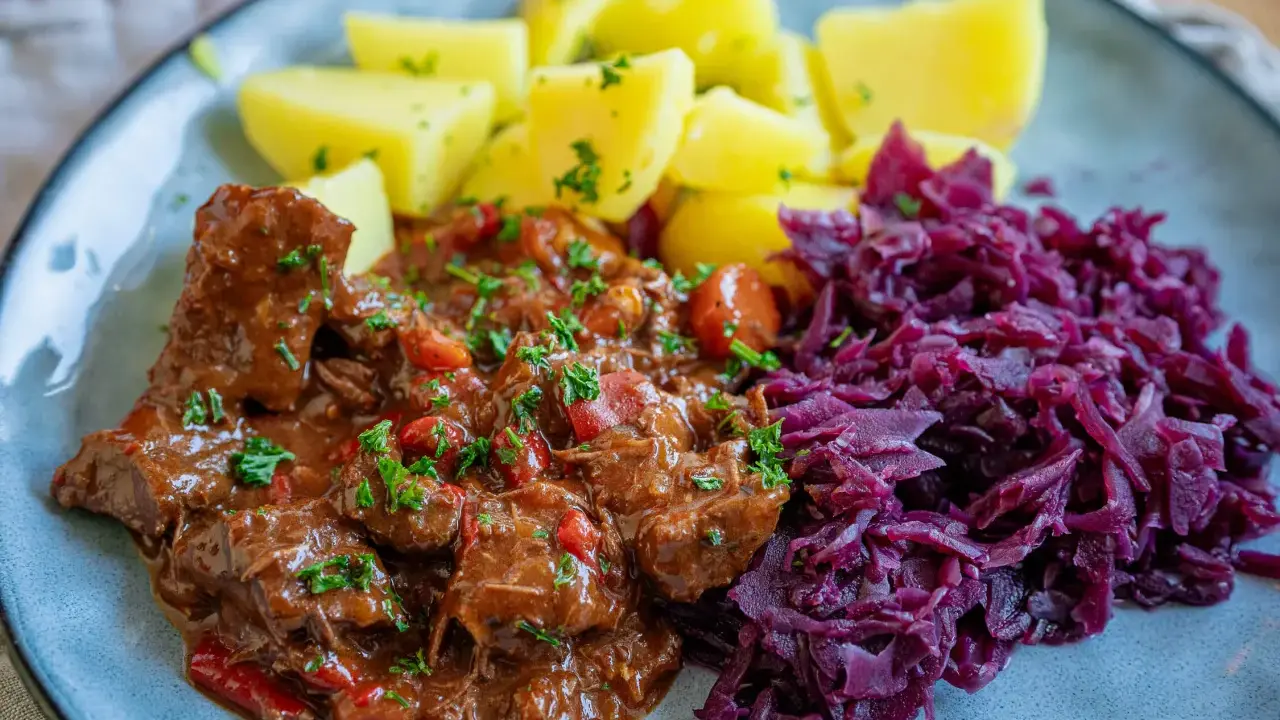 Herzhaftes Gulasch mit Kartoffeln und Rotkohl, inspiriert von Gulaschkanone Rezepten.