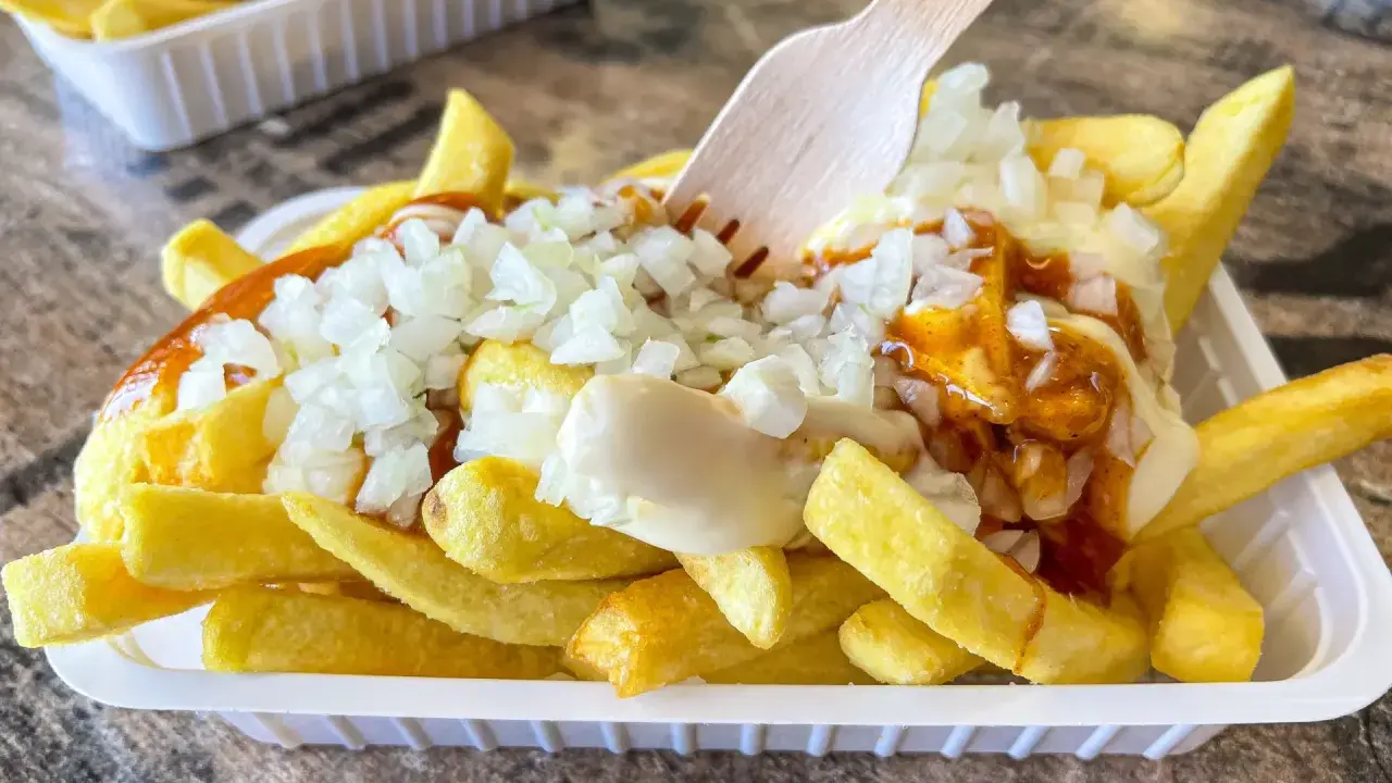 Pommes Spezial: goldgelbe Pommes mit Mayonnaise, Zwiebeln und einer würzigen Sauce, bereit zum Genuss.