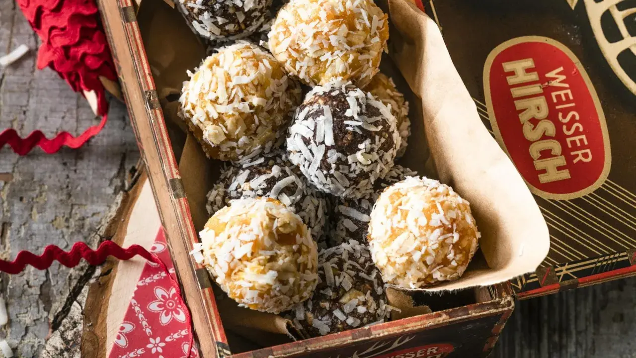 Leckere energy balls selber machen! Eine Mischung aus dunklen und hellen Kugeln, umhüllt von Kokosraspeln, in einer alten Blechdose.