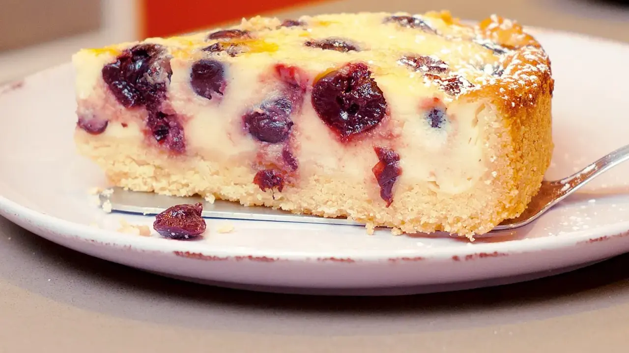 Ein Stück Kirsch-Schmand-Kuchen, wie ihn Landfrauen backen, mit saftigen Kirschen und Puderzucker bestäubt.