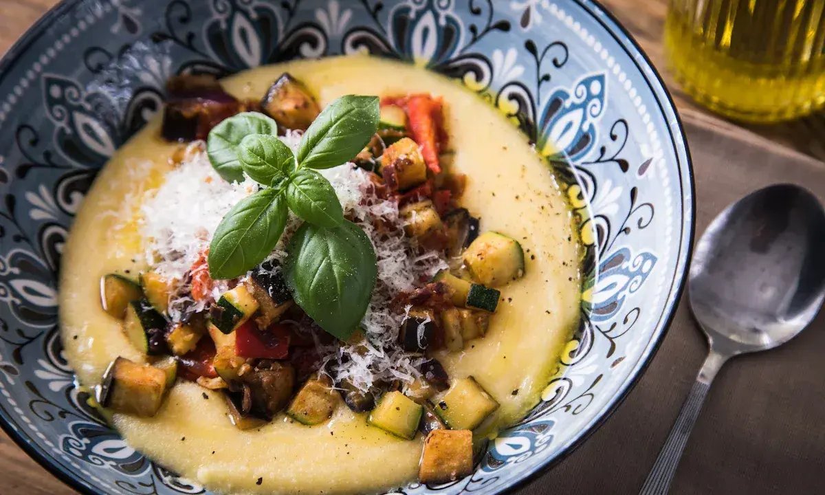 Cremige Polenta mit gebratenem Gemüse, Parmesan und Basilikum. So ist Polenta genau richtig: ein herzhaftes Gericht, das wärmt.