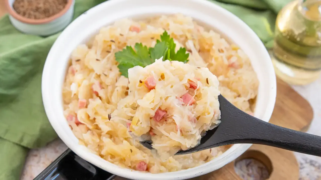 Herzhaftes Sauerkraut nach Hausfrauenart mit Speck und Kümmel, garniert mit Petersilie. Ein Löffel voller Tradition.