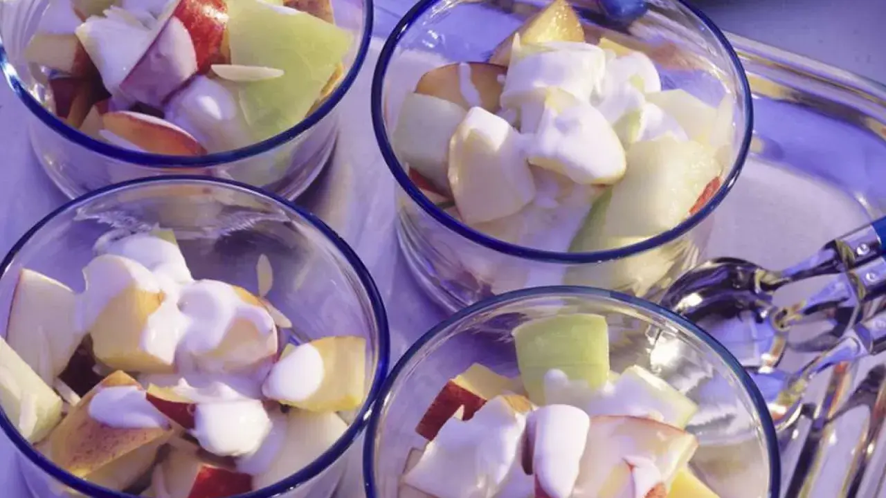 Vier Gläser mit einem erfrischenden Nachtisch mit griechischem Joghurt und Obststücken.