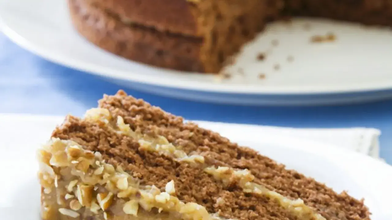 Ein Stück saftige Nusstorte mit cremiger Buttercreme und gehackten Nüssen, bereit zum Genießen.