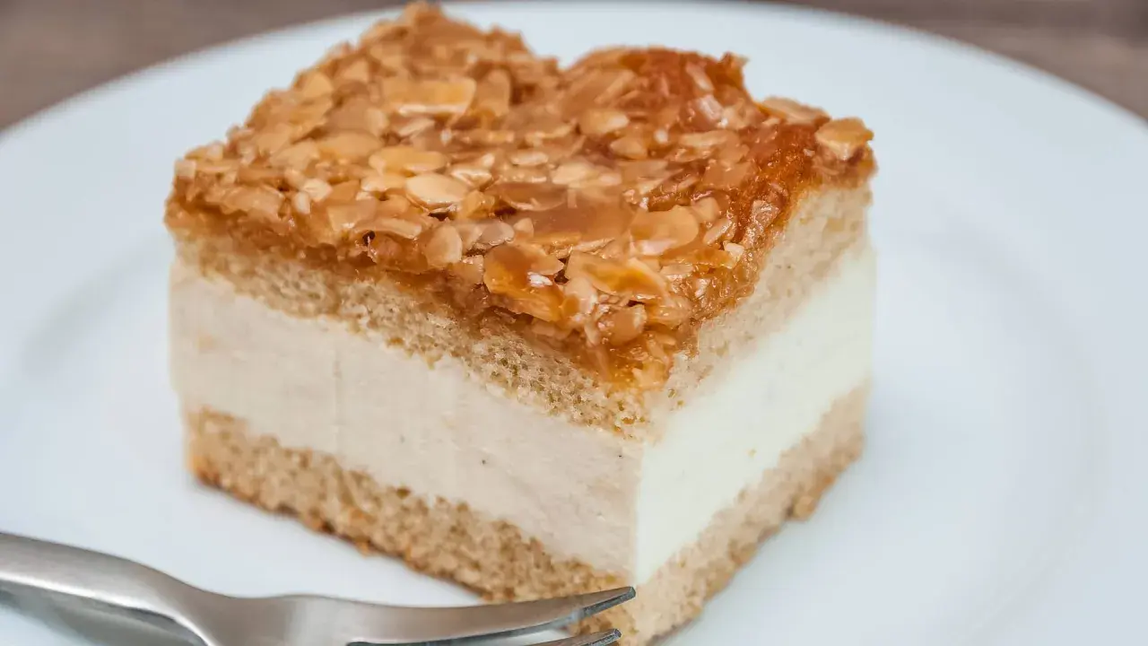 Ein Stück Kuchen mit cremiger Füllung und karamellisierten Mandeln. Der Kuchen wird zu dunkel, aber die Mandeln sind perfekt gebräunt.