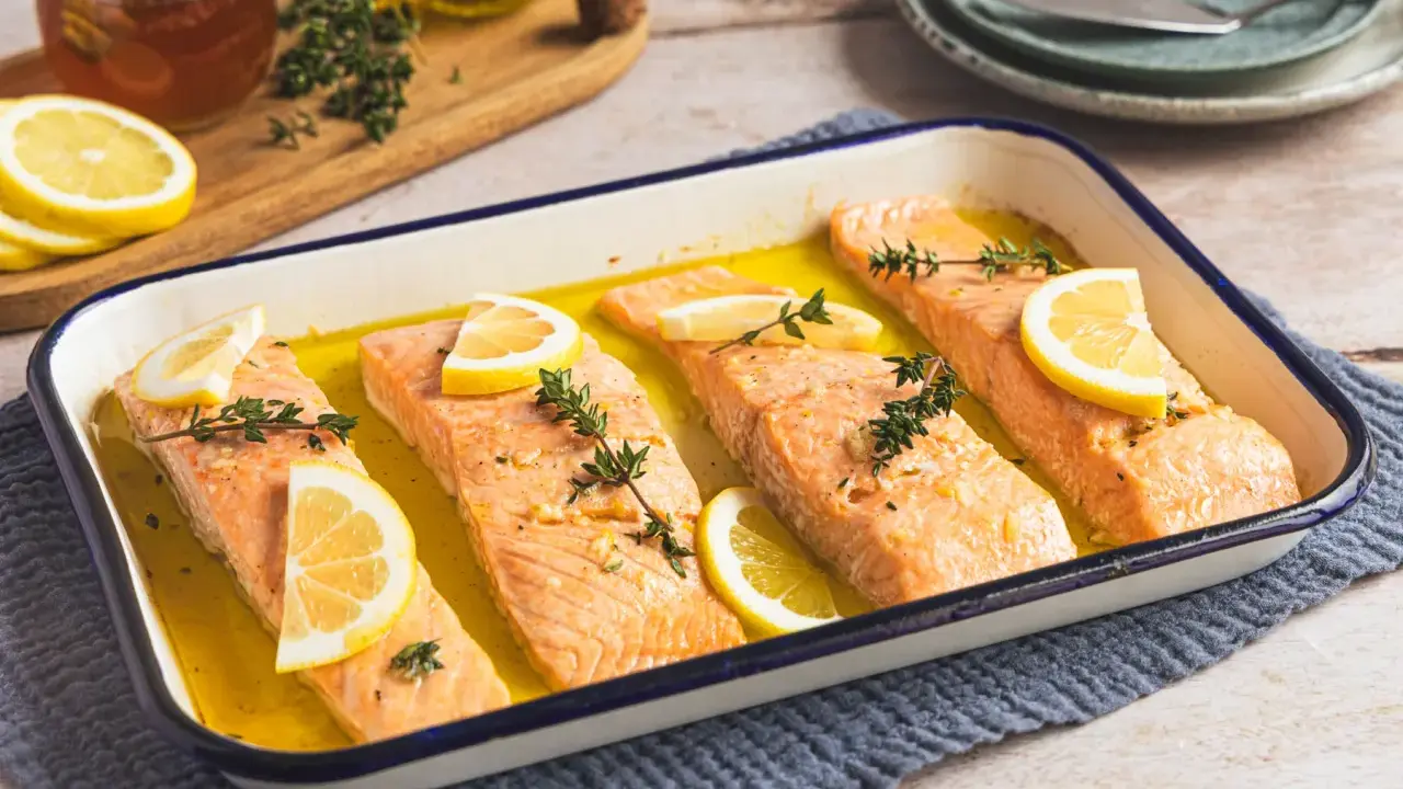 Vier Lachsfilets mit Zitrone und Thymian in einer Auflaufform, bereit für den Ofen. Perfekt für einfache Lachs Rezepte Ofen.