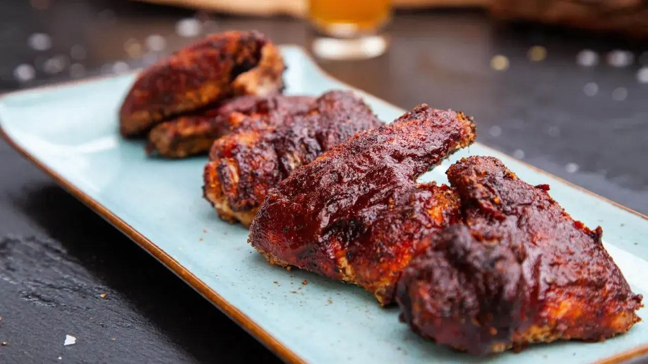 Saftige chicken wings in einer würzigen Marinade, serviert auf einem hellblauen Teller.
