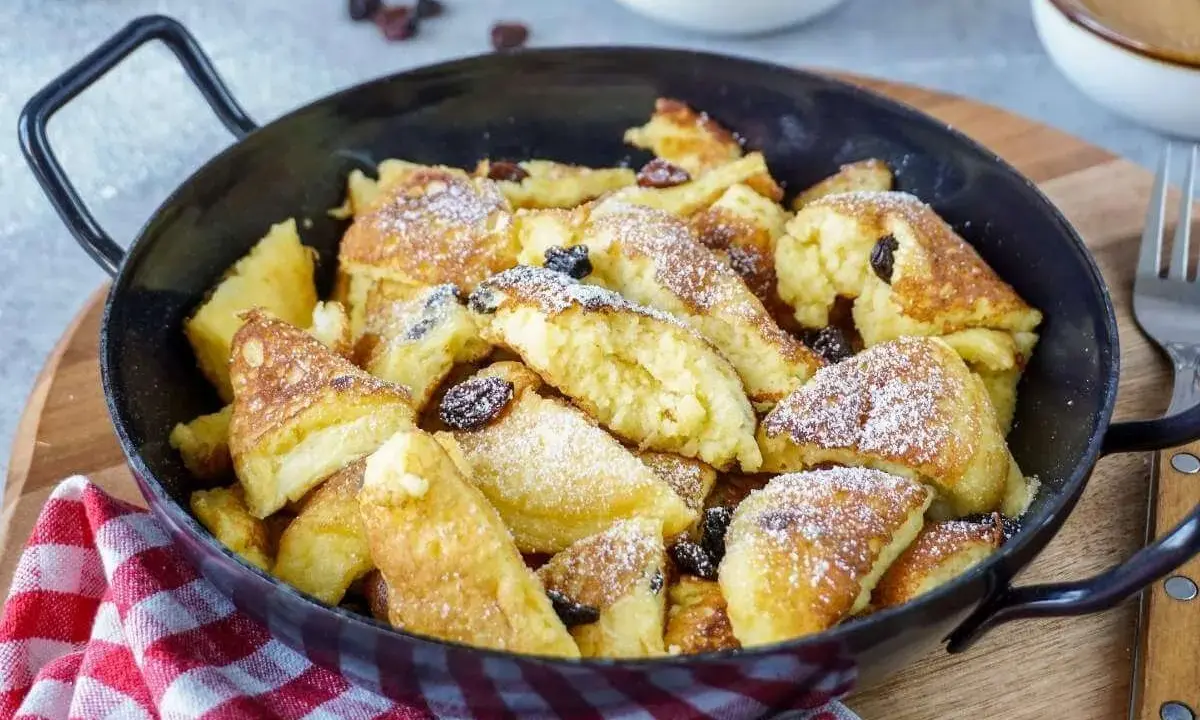 Kaiserschmarrn, fluffig und goldbraun, mit Rosinen und Puderzucker bestreut, zubereitet im Thermomix.
