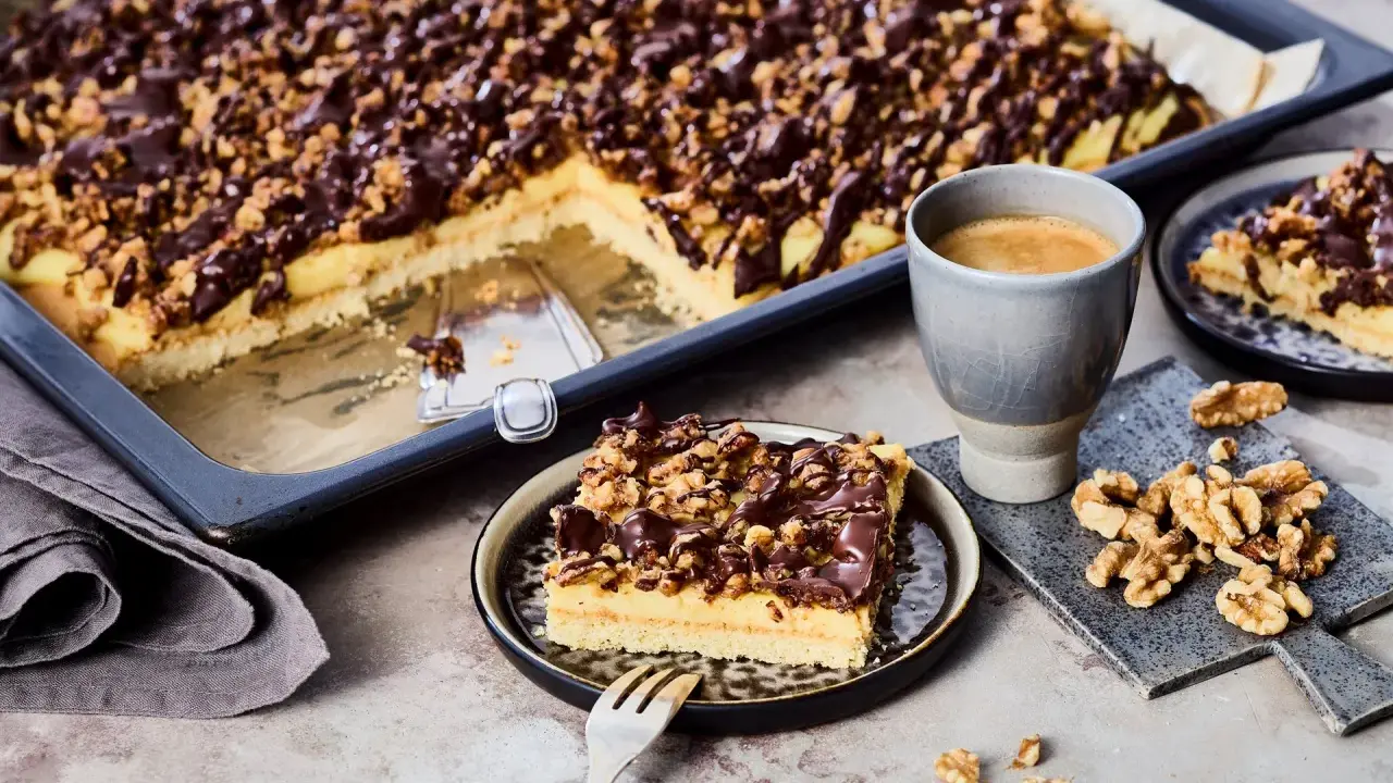 Ein Stück "friss dich dumm Kuchen" mit Schokoladen-Nuss-Decke und einer Tasse Kaffee.