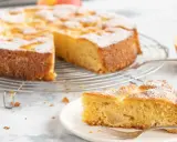 Ein saftiger glutenfreier Apfelkuchen, bestäubt mit Puderzucker, auf einem Gitterrost. Ein Stück auf einem Teller mit Gabel daneben.