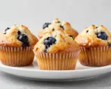 Vier saftige Blaubeermuffins, perfekt gebacken im Philips Airfryer, auf einem weißen Teller.