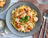 Tagliatelle al salmone mit Kirschtomaten und Parmesan, garniert mit Basilikum. Ein köstliches Gericht, das Lust auf mehr macht.