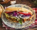 Saftiger Döner Kebab mit Fleisch, Salat, Tomaten, Zwiebeln und Rotkohl auf einem Teller. Ein leckeres Kebab Rezept zum Nachmachen.