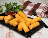 Goldbraune Kroketten, frisch zubereitet, liegen auf einem schwarzen Teller. Dazu gibt es Ketchup und frische Petersilie. Perfekt zum kroketten selber machen!
