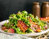 Salat mit Rucola, roten Zwiebeln und knusprigem Speck. Perfekte warme Beilagen zum Salat, die für zusätzlichen Geschmack sorgen.