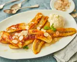 Gebackene Bananen mit einer Kugel Eis, garniert mit Mandelblättchen und Minze. Ein süßer Genuss!