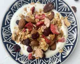 Schüssel mit Joghurt, selbstgemachtem Crunch, Mandeln, gefriergetrockneten Erdbeeren und Blaubeeren.