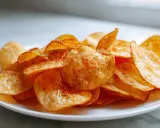 Knusprige Kartoffelchips, gewürzt mit Paprikapulver, frisch aus dem Airfryer auf einem Teller.