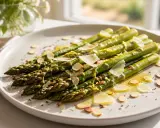 Gebratener Spargel mit Parmesan und Mandelsplittern auf einem Teller, garniert mit Zitronenschale.