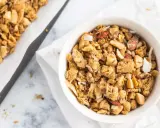 Schüssel mit selbstgemachtem, gesundem Granola, Nüssen und Kokosflocken. Daneben ein Blech mit frisch gebackenem Müsli.