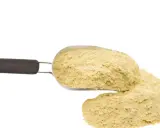 Ein Löffel mit gelblichen Hefeflocken, die als köstlicher hefeflocken ersatz dienen.