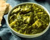 Schüssel mit cremigem Palak Paneer, einem indischen Gericht aus Spinat und Käse, daneben Fladenbrot.
