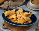 Kaiser­sch­marrn, ein Klassiker der besten Thermomix Rezepte, bestäubt mit Puderzucker auf einem blauen Teller.