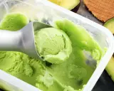 Cremiges, grünes veganes Eis, perfekt zum veganes Eis selber machen mit Mandelmilch. Avocados und Waffeln im Hintergrund.