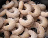 Ein Haufen frisch gebackener Vanillekipferl, bedeckt mit feinem Zucker, wartet darauf, genossen zu werden.