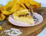 Ein Stück cremiger Milchreiskuchen auf rosa Teller, daneben roher Reis. Ein leckeres Milchreiskuchen Rezept zum Nachbacken.