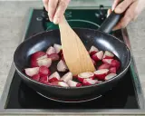 Schnittradieschen werden in einer Pfanne mit einem Holzspatel gewendet.