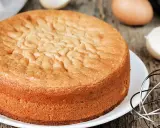 Ein goldbrauner Biskuitboden, perfekt für jedes biskuitboden rezept. Eier und Schneebesen deuten auf die Zubereitung hin.