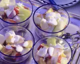 Vier Gläser mit einem erfrischenden Nachtisch mit griechischem Joghurt und Obststücken.