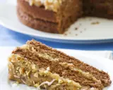 Ein Stück saftige Nusstorte mit cremiger Buttercreme und gehackten Nüssen, bereit zum Genießen.