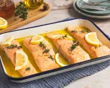 Vier Lachsfilets mit Zitrone und Thymian in einer Auflaufform, bereit für den Ofen. Perfekt für einfache Lachs Rezepte Ofen.