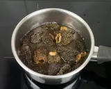 Getrocknete Morcheln werden in einem Topf mit Wasser eingeweicht, um sie für die Zubereitung vorzubereiten.