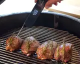 Vier Hirschsteaks mit Rosmarin auf dem Grill, ein Thermometer zeigt 48°C an. So gelingt das Hirschsteak richtig braten.