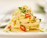 Ein Berg von Spaghetti Aglio e Olio, garniert mit frischer Petersilie und scharfen Chilischeiben.