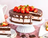 Ein saftiger Erdbeerkuchen mit Schokolade, dekoriert mit frischen Erdbeeren und Schokoladenglasur. Ein Stück ist bereits angeschnitten.