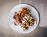 Ein köstlicher Somlauer Nockerl-Dessert auf einem Teller, mit Schokoladensauce und Eiscreme garniert.